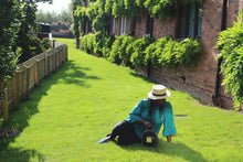 Load image into Gallery viewer, Lady seated on grass holding black Boye bag
