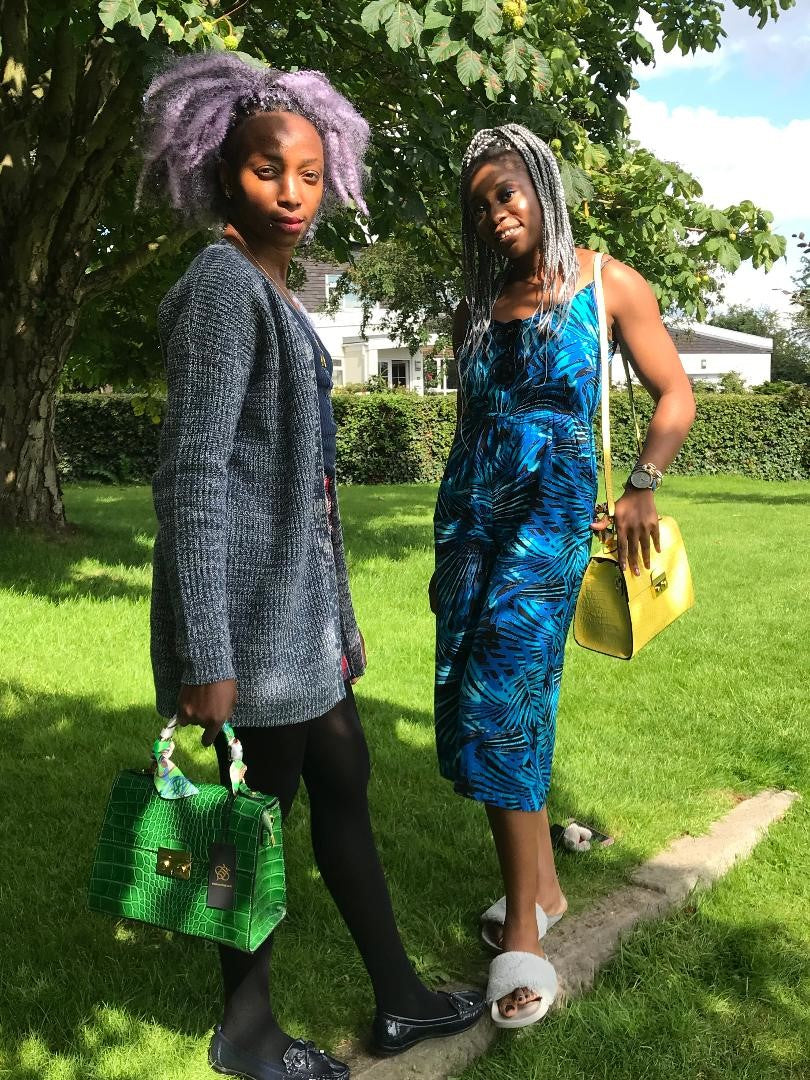 Two ladies in park holding Green and Yellow Crocodile embossed leather bags