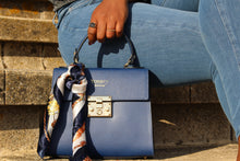 Load image into Gallery viewer, Lady in jeans seated on bench with blue Kelly Bovine Leather bag